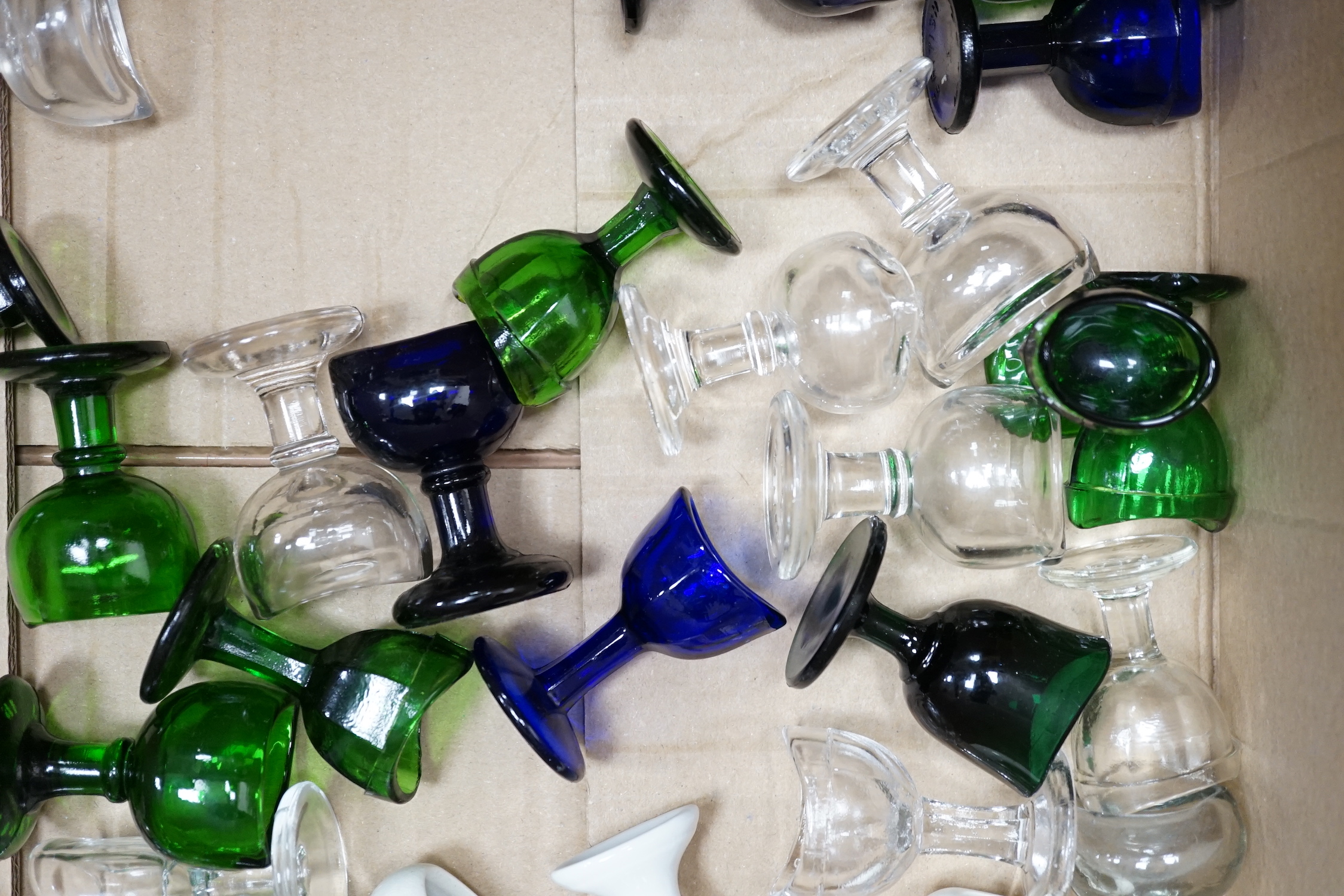 Thirty-four glass and porcelain eye baths, including green and blue glass examples